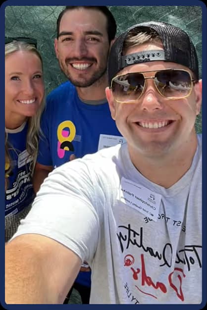 Three smiling adults taking a close-up selfie outdoors